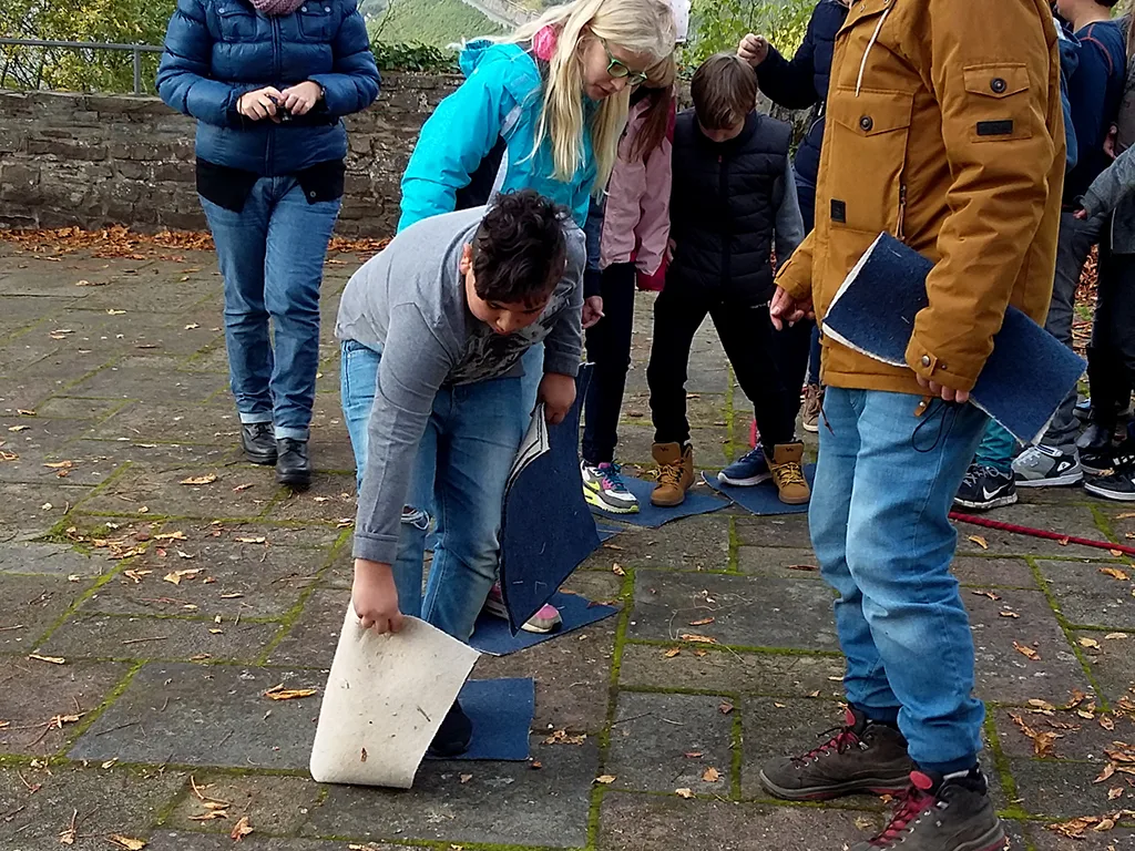 Gruppe beugt sich über eine Aufgabe am Boden.